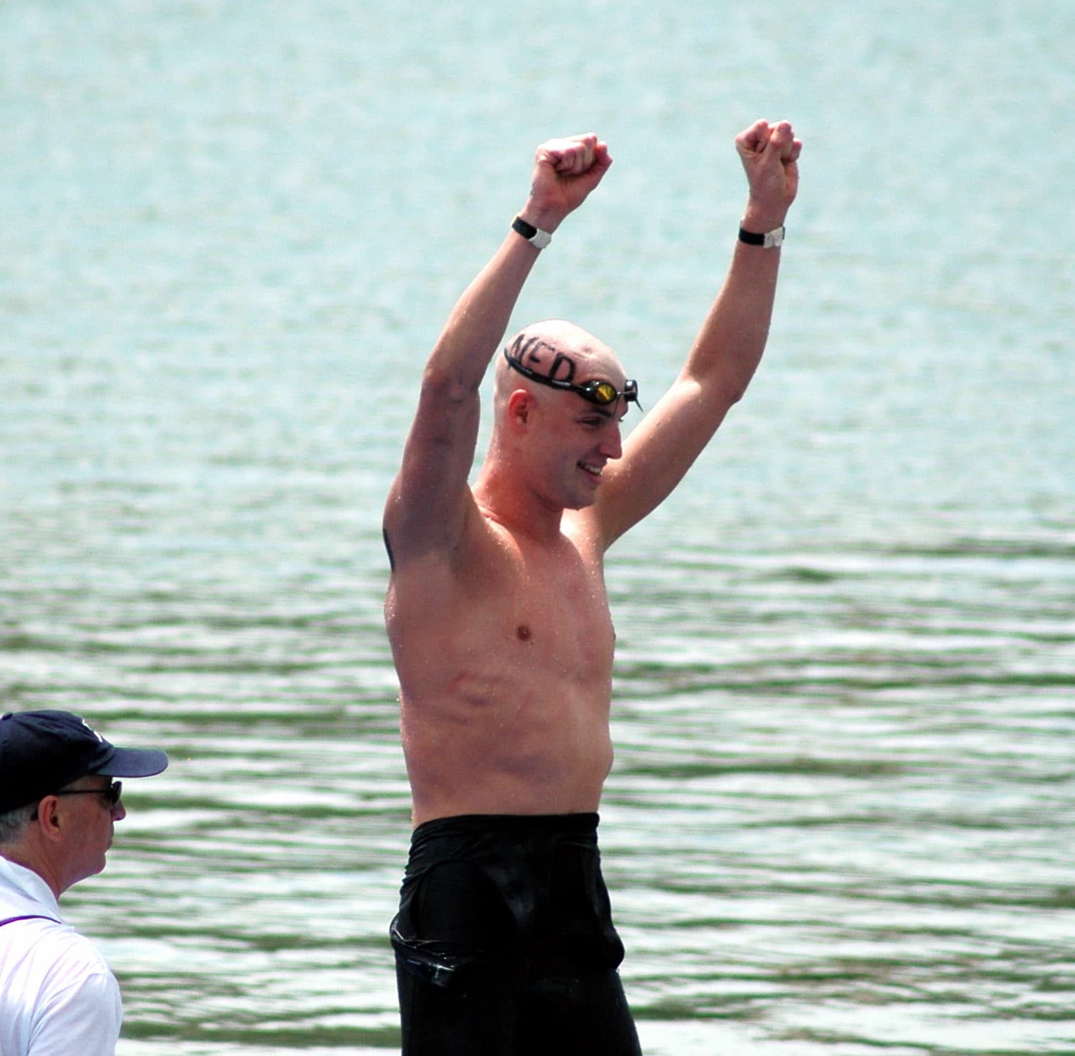 Maarten juicht met gebalde vuisten in het open water, met NED op zijn hoofd geschreven