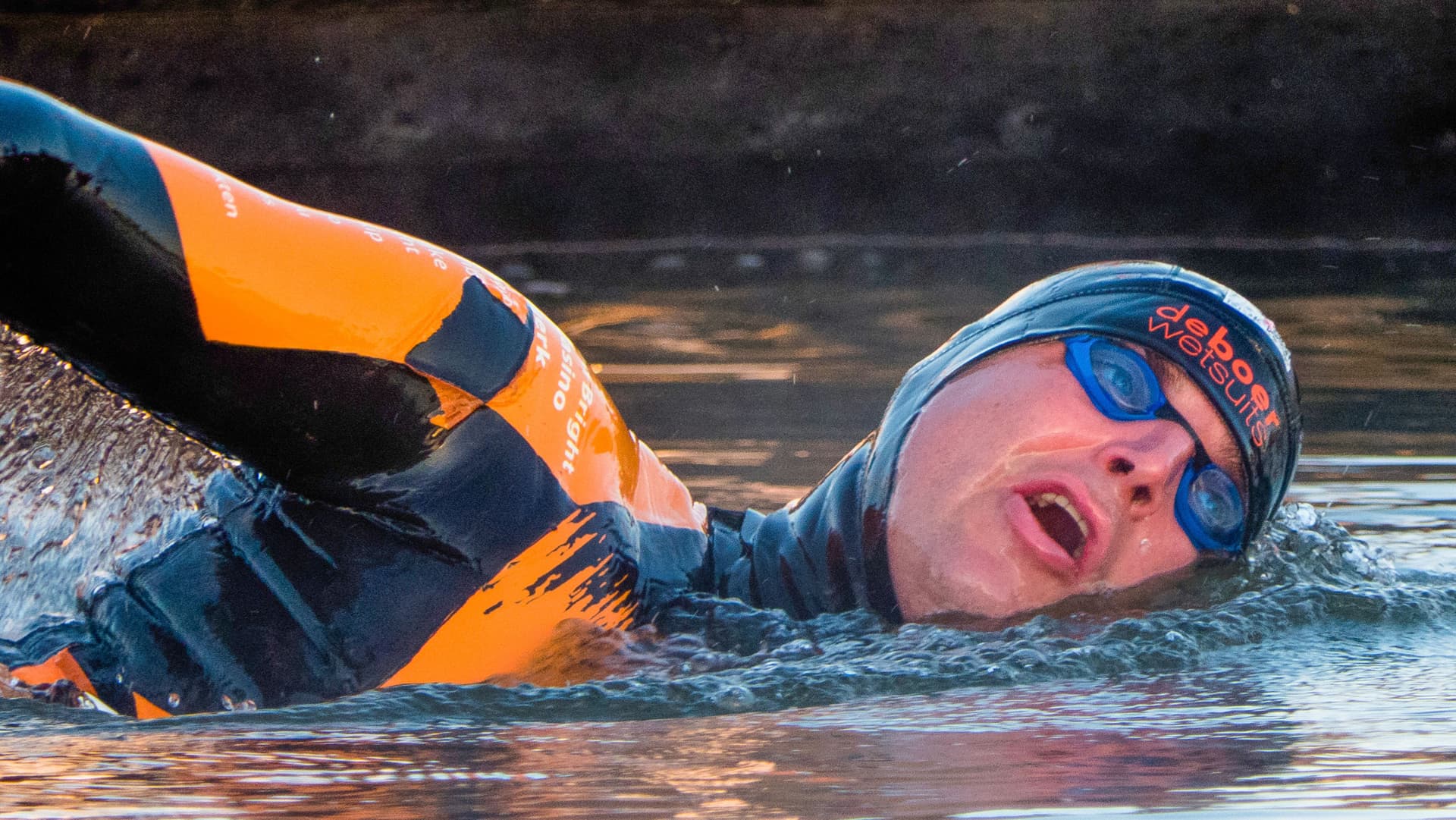 Maarten zwemt in een oranje wetsuit tijdens de Elfstedentocht van 2019