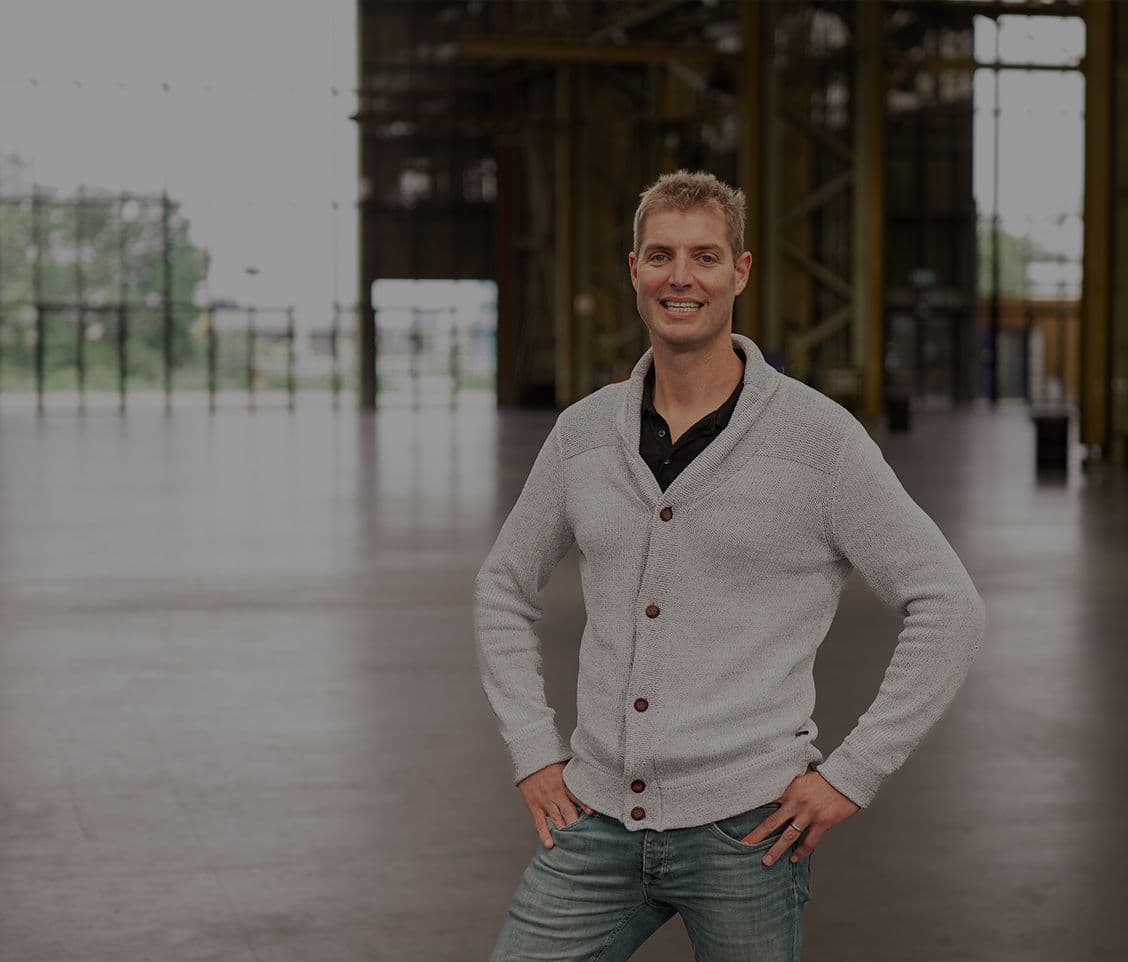 Maarten van der Weijden standing in an industrial hall with large windows